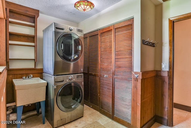 washroom with sink, a textured ceiling, and stacked washer and dryer