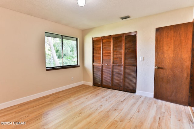 unfurnished bedroom with light hardwood / wood-style floors and a closet