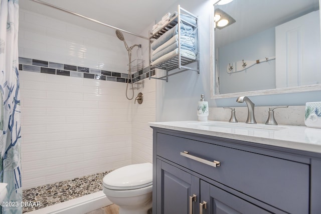 bathroom featuring vanity, toilet, and tiled shower