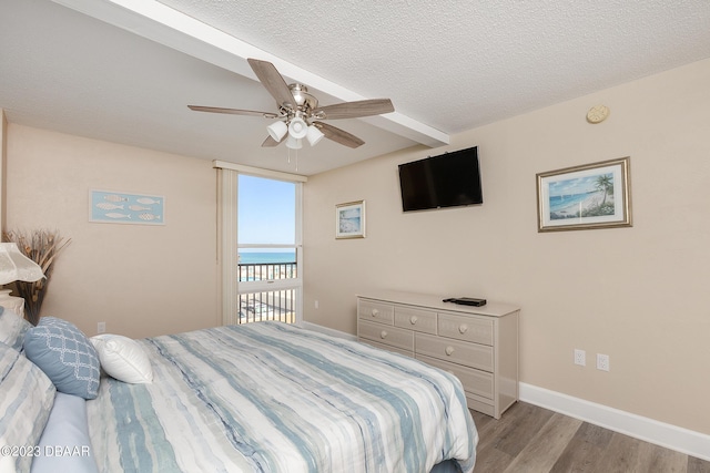 bedroom with ceiling fan, light wood-style flooring, baseboards, and a textured ceiling