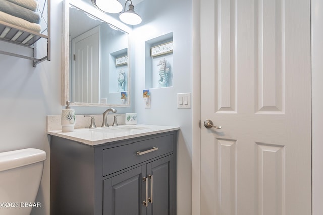 half bath featuring vanity and toilet