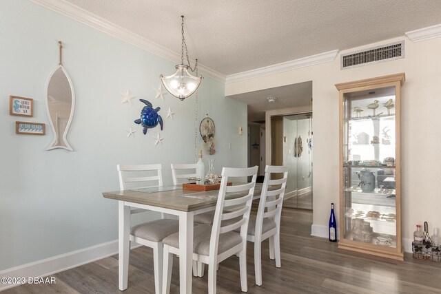 dining room with visible vents, a textured ceiling, wood finished floors, and ornamental molding