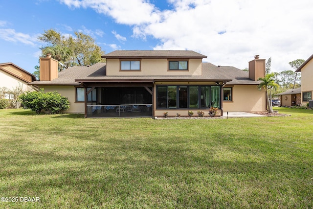 rear view of property with a yard, a patio area, and a sunroom