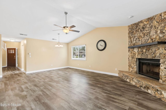 unfurnished living room with ceiling fan with notable chandelier, lofted ceiling, a stone fireplace, and hardwood / wood-style floors