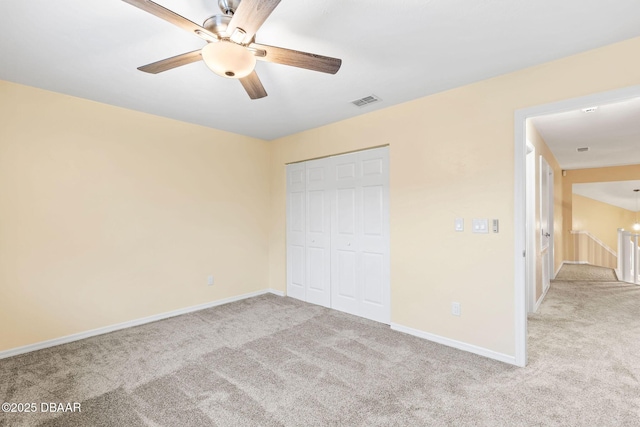 unfurnished bedroom featuring ceiling fan, a closet, and light carpet