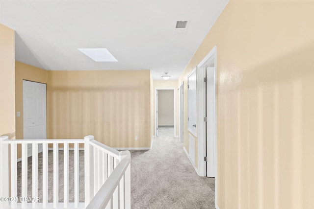 corridor featuring light colored carpet and a skylight