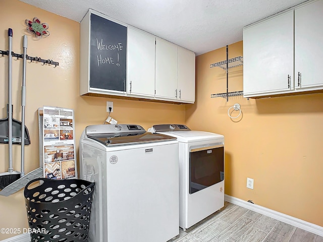 laundry area with washer and clothes dryer, cabinets, and a textured ceiling