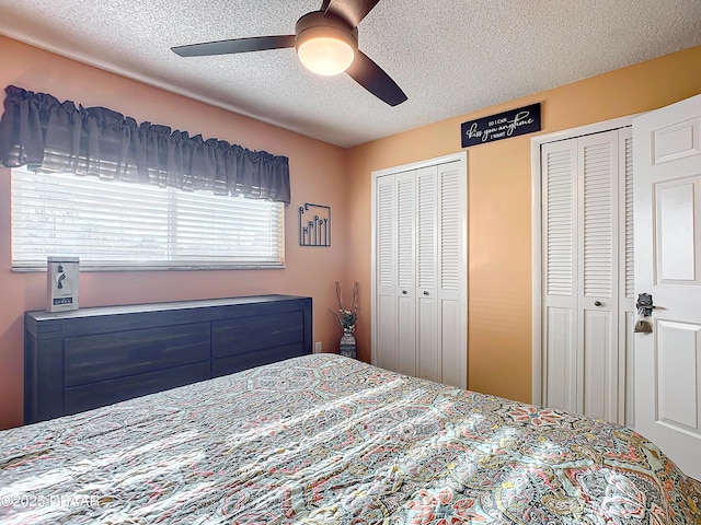 bedroom with ceiling fan, a textured ceiling, and two closets