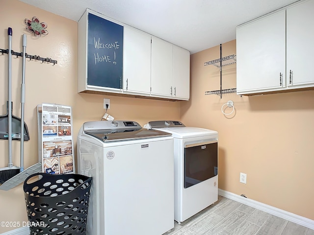 clothes washing area featuring separate washer and dryer and cabinets