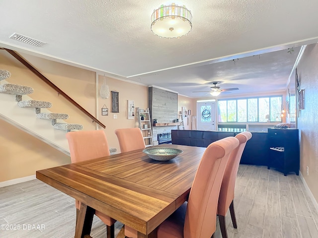 dining room featuring ceiling fan, light hardwood / wood-style floors, and a textured ceiling