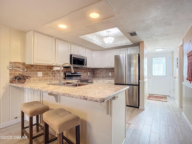 kitchen with a breakfast bar area, white cabinetry, light hardwood / wood-style flooring, and appliances with stainless steel finishes