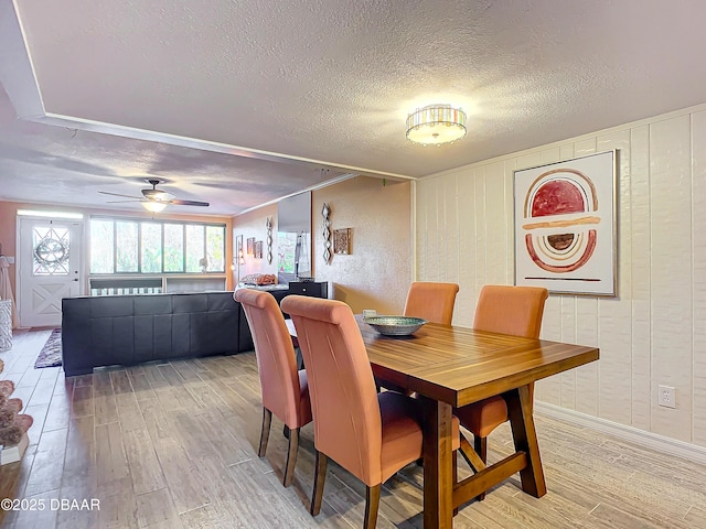 dining area featuring ceiling fan, wood-type flooring, and a textured ceiling