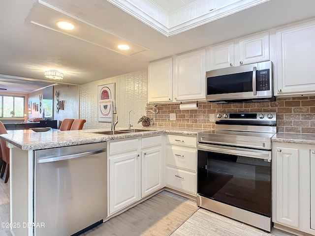 kitchen featuring white cabinets, stainless steel appliances, kitchen peninsula, and sink