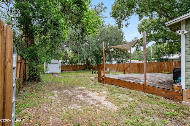 view of yard featuring an outbuilding, a storage unit, a fenced backyard, and a wooden deck