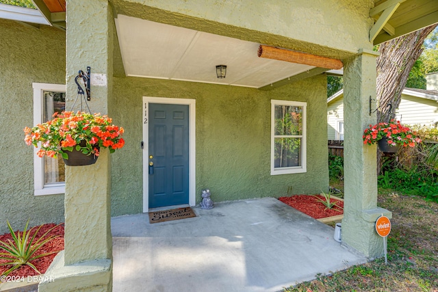 property entrance with fence and stucco siding