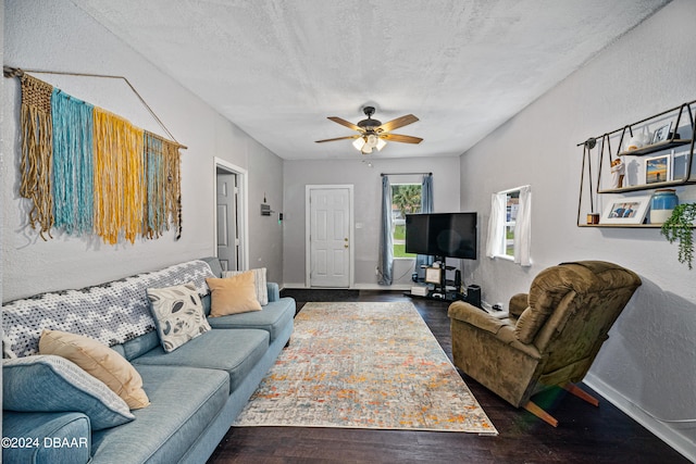 living area with a textured wall, ceiling fan, a textured ceiling, wood finished floors, and baseboards