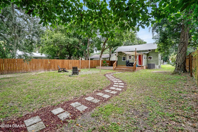 view of yard featuring a wooden deck, a fire pit, and central AC unit