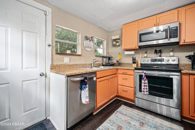 kitchen featuring dark wood-type flooring, a sink, stainless steel appliances, light countertops, and backsplash