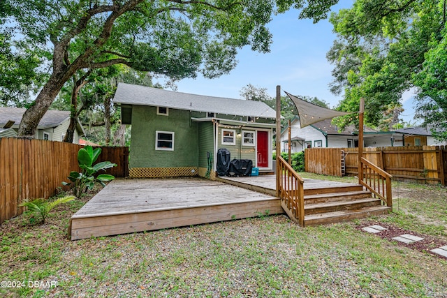 rear view of property featuring a fenced backyard, a deck, and stucco siding