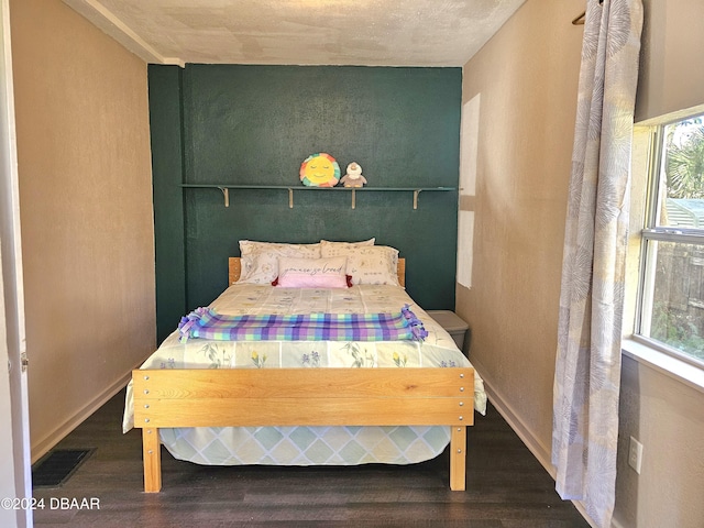 bedroom with wood finished floors, visible vents, and baseboards