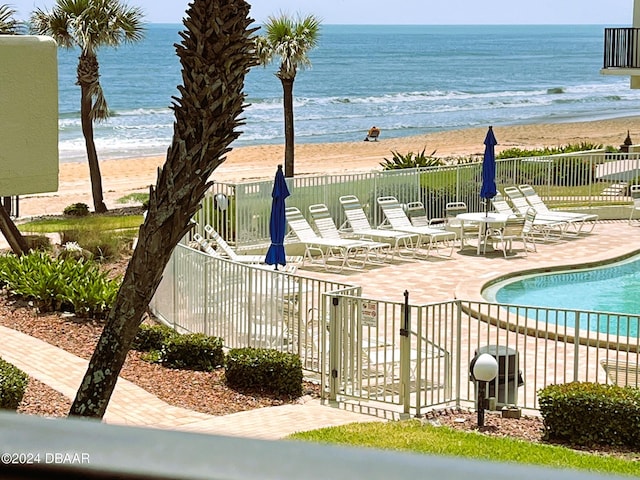 view of swimming pool with a view of the beach, a patio, and a water view