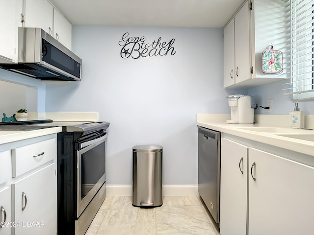 kitchen with stainless steel appliances, white cabinetry, and sink