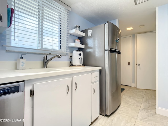 kitchen featuring white cabinetry, stainless steel appliances, a textured ceiling, and sink