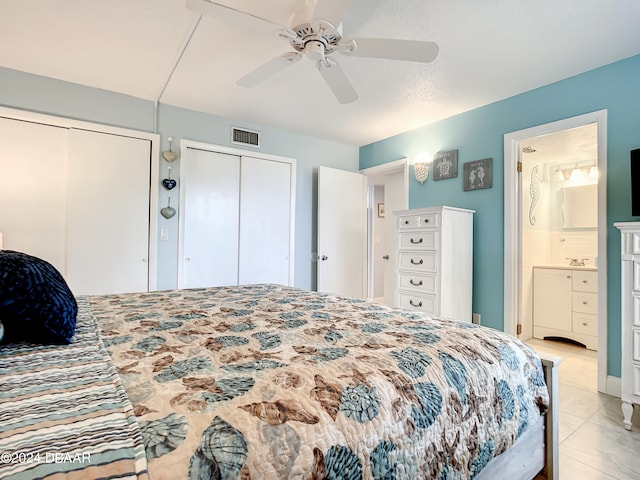 tiled bedroom featuring multiple closets, ceiling fan, and connected bathroom