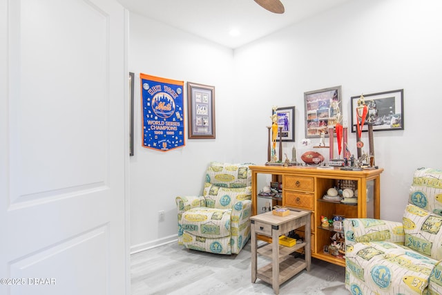 living area with ceiling fan and light hardwood / wood-style flooring