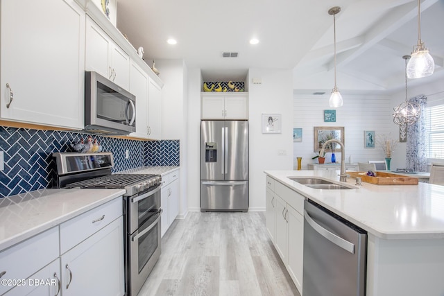 kitchen with pendant lighting, white cabinetry, sink, stainless steel appliances, and a center island with sink