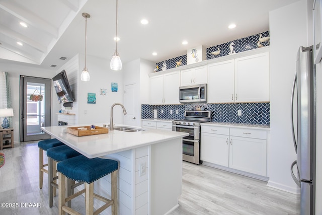 kitchen featuring sink, white cabinetry, appliances with stainless steel finishes, an island with sink, and pendant lighting