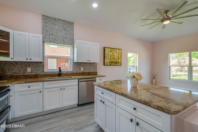 707 Hamilton St, New Smyrna Beach, FL 32168 - kitchen with a sink, stainless steel dishwasher, decorative backsplash, light wood finished floors, and white cabinetry