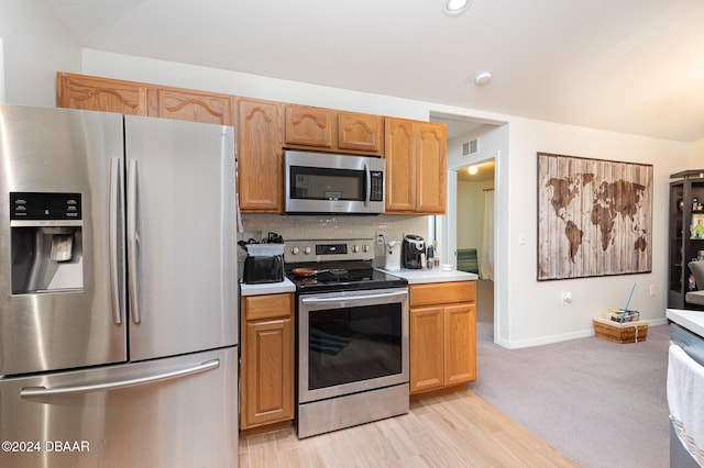 kitchen with stainless steel appliances, tasteful backsplash, and light hardwood / wood-style floors