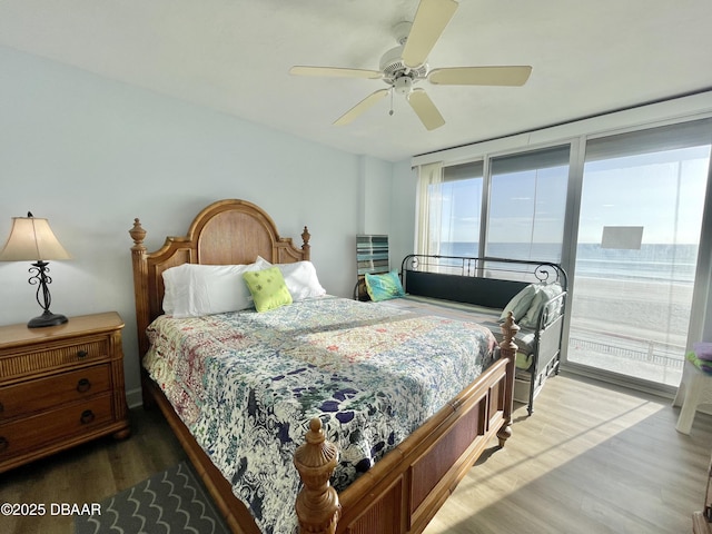 bedroom with ceiling fan, expansive windows, and wood-type flooring