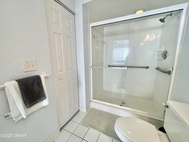 bathroom with tile patterned floors, walk in shower, and toilet