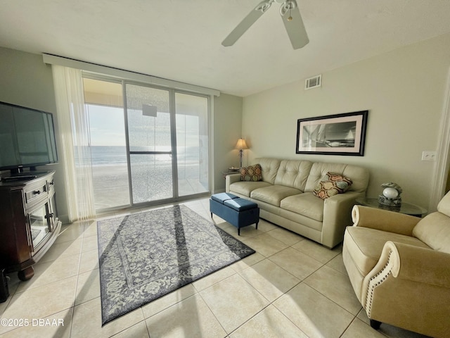 living room with light tile patterned flooring, a water view, and ceiling fan