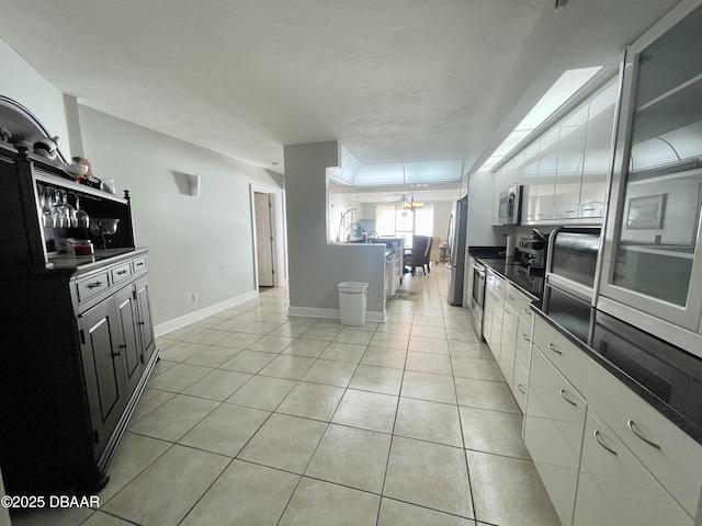 kitchen with light tile patterned flooring, white cabinets, and appliances with stainless steel finishes