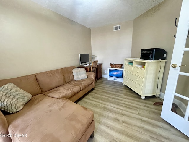 living room with light hardwood / wood-style flooring and a textured ceiling