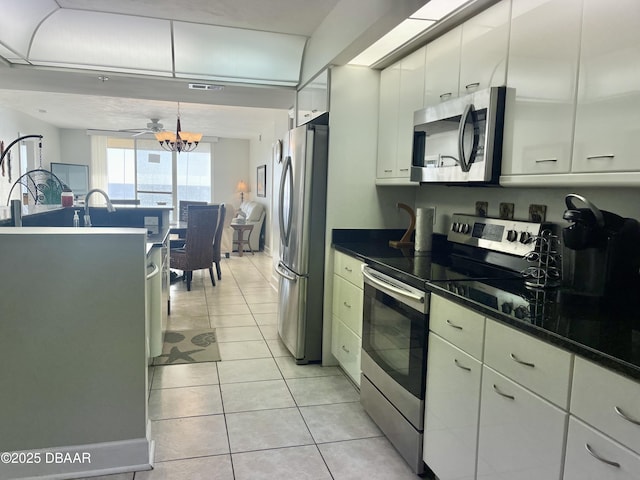 kitchen with light tile patterned floors, white cabinetry, appliances with stainless steel finishes, and a chandelier