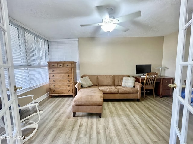 living room featuring a textured ceiling, a healthy amount of sunlight, french doors, and light wood-type flooring