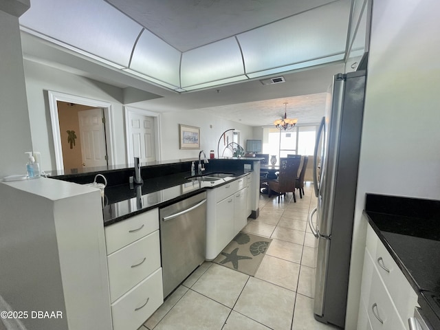 kitchen featuring appliances with stainless steel finishes, white cabinetry, a chandelier, light tile patterned floors, and sink