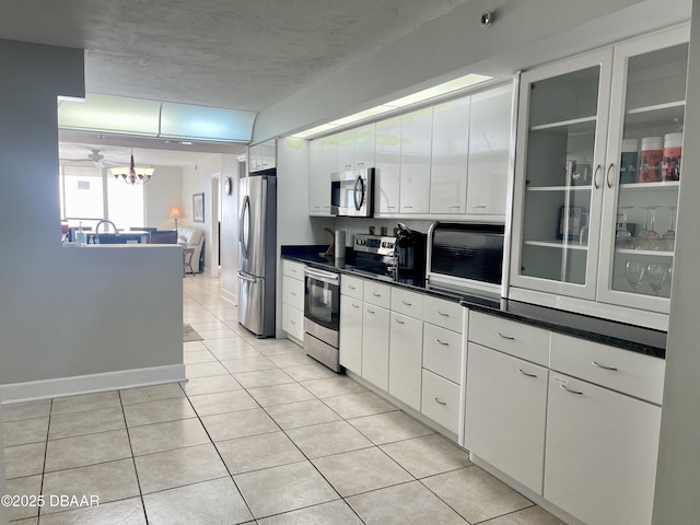 kitchen with light tile patterned flooring, white cabinetry, a notable chandelier, and stainless steel appliances