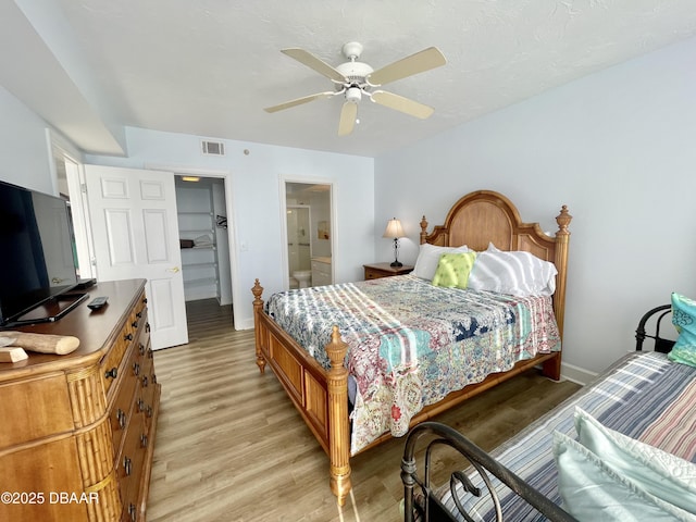 bedroom featuring ceiling fan, light hardwood / wood-style floors, a closet, and a walk in closet