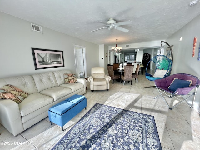 tiled living room with ceiling fan with notable chandelier and a textured ceiling