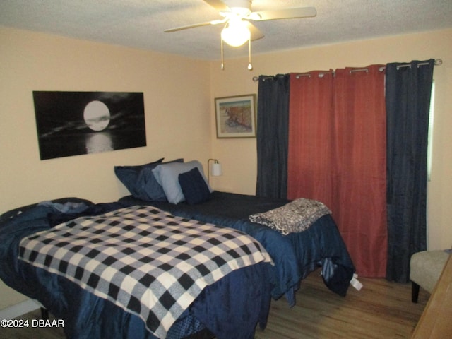 bedroom with hardwood / wood-style floors, ceiling fan, and a textured ceiling