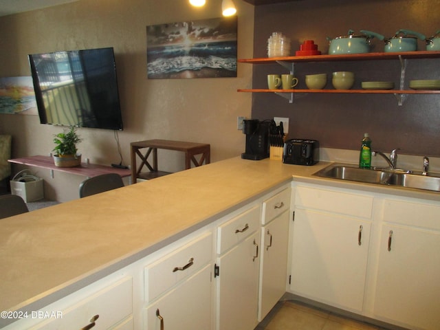 kitchen featuring white cabinetry, sink, and light tile patterned floors