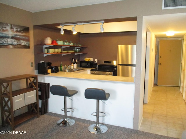 kitchen with kitchen peninsula, rail lighting, stainless steel appliances, sink, and a breakfast bar area