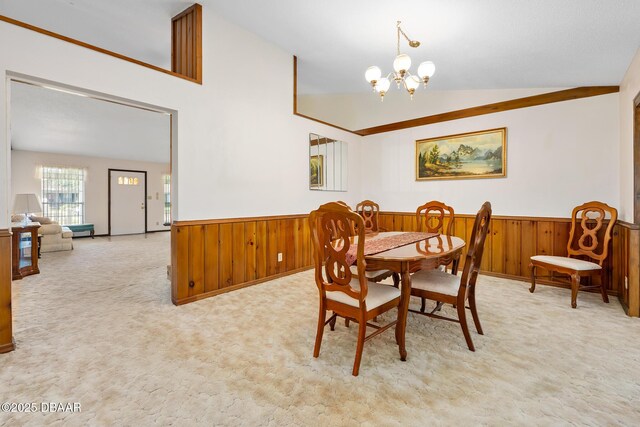 carpeted dining space with vaulted ceiling and a notable chandelier