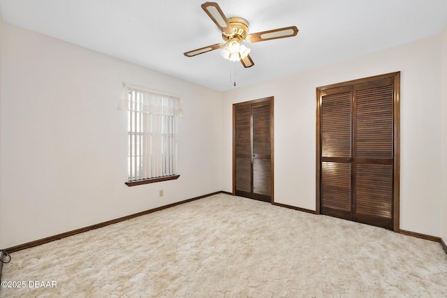 unfurnished bedroom with multiple closets, ceiling fan, and light colored carpet