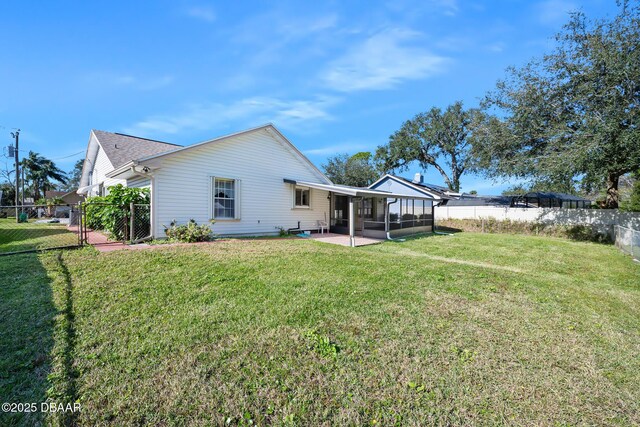 rear view of house featuring a patio, a lawn, and a sunroom